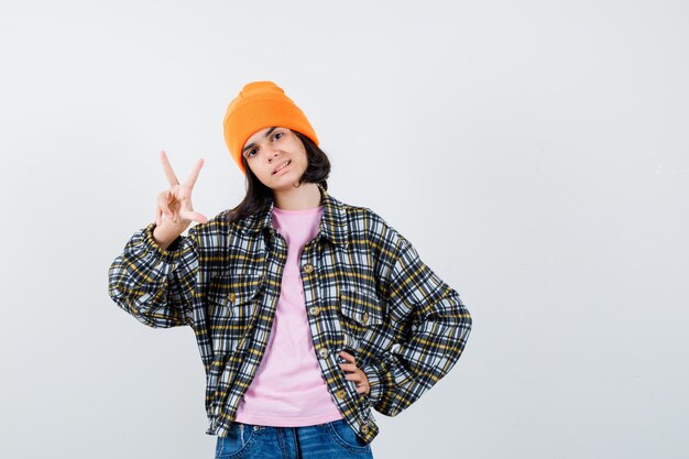 Teen woman in checkered shirt and beanie gesticulating isolated