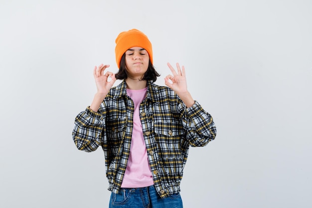 Teen woman in checkered shirt and beanie gesticulating isolated