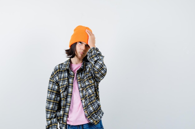 Teen woman in checkered shirt and beanie gesticulating isolated