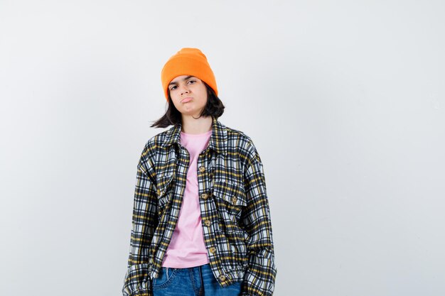 Teen woman in checkered shirt and beanie gesticulating isolated