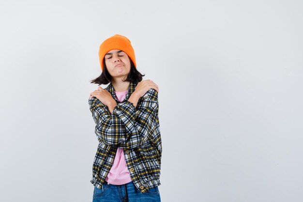 Teen woman in checkered shirt and beanie gesticulating isolated