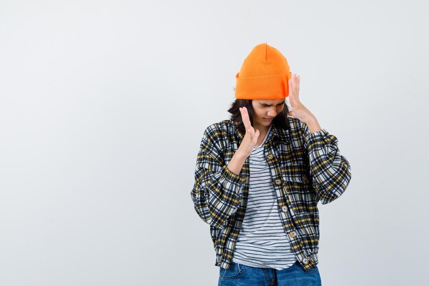 Teen woman in checkered shirt and beanie gesticulating isolated