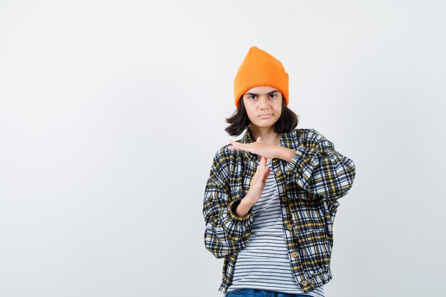 Teen woman in checkered shirt and beanie gesticulating isolated