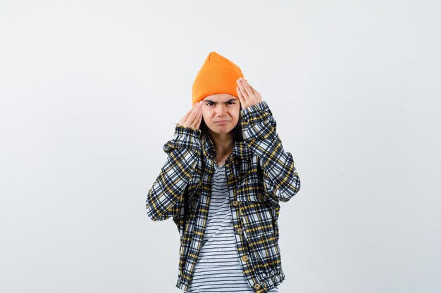 Teen woman in checkered shirt and beanie gesticulating isolated