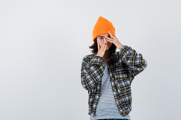 Teen woman in checkered shirt and beanie gesticulating isolated