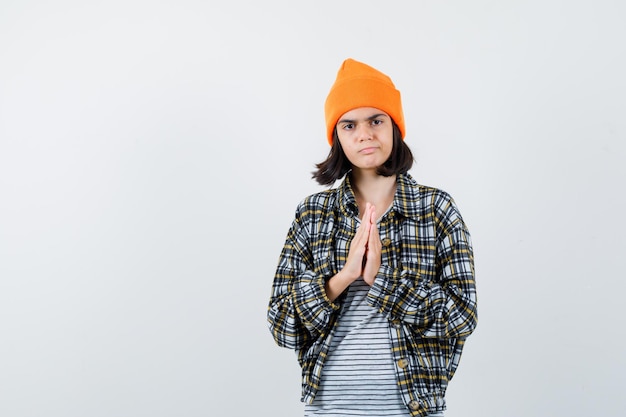 Teen woman in checkered shirt and beanie gesticulating isolated