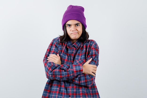 Teen woman in checkered shirt and beanie gesticulating isolated