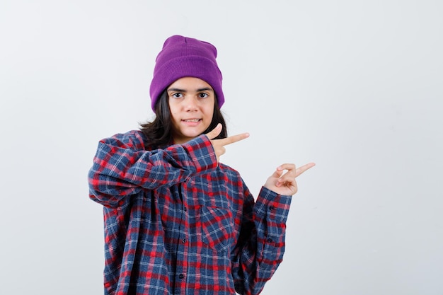 Teen woman in checkered shirt and beanie gesticulating isolated