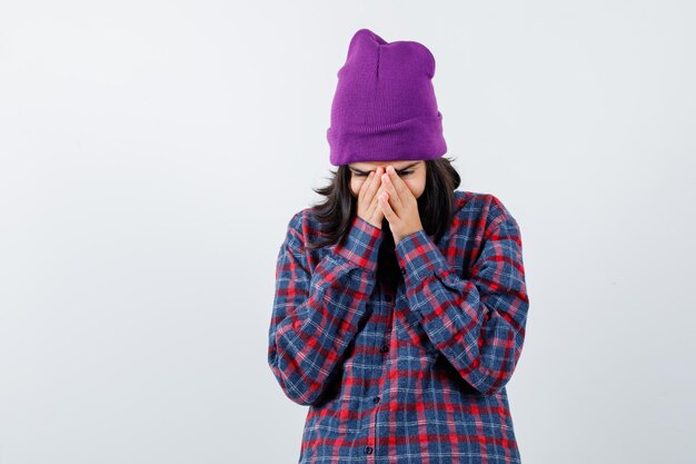 Teen woman in checkered shirt and beanie gesticulating isolated