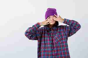 Free photo teen woman in checkered shirt and beanie rubbing eyes with hands