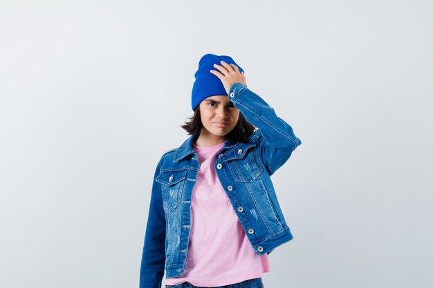 Teen woman holding hand on head looking worried