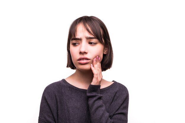 Teen woman pressing her bruised cheek with a painful expression as if she's having a terrible tooth ache.