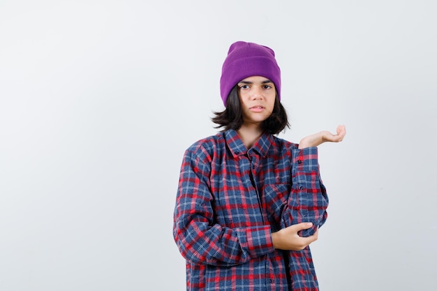 Teen woman pretending to whow something in checkered shirt looking focused