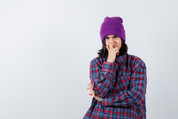 Teen woman propping chin on hand beanie looking pensive 