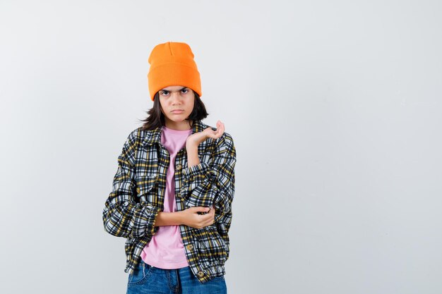 Teen woman in t-shirt while raising hand looking serious