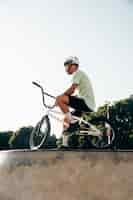 Foto gratuita cavaliere adolescente del bmx che sta con la sua vista di angolo basso della bici