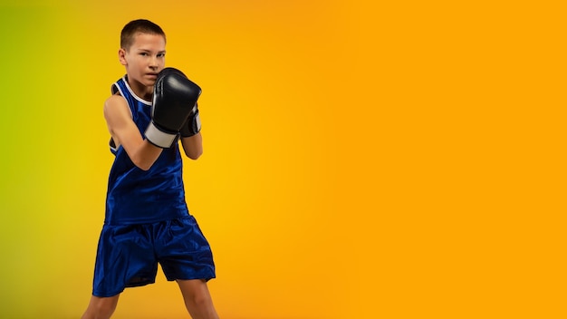 Free photo teenage boxer against gradient neon studio in motion of kicking, boxing