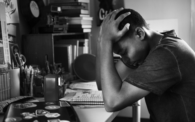 Teenage boy in a bedroom doing work stressed out and frustrated