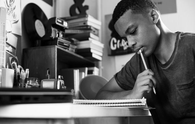 Teenage boy in a bedroom doing work thinking