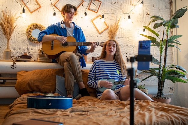 Free photo teenage boy and girl recording music at their home studio with guitar