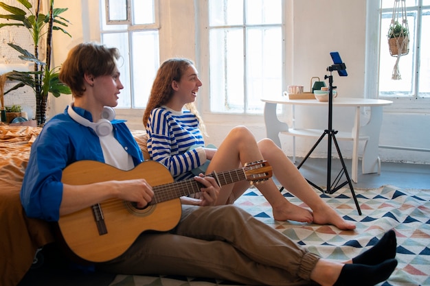 Adolescente e ragazza che registrano musica nel loro studio di casa con la chitarra