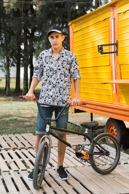 Teenage boy holding his bicycle at park