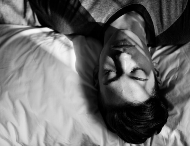 Подросток, лежа на кровати, сонный сон и концепция депрессии