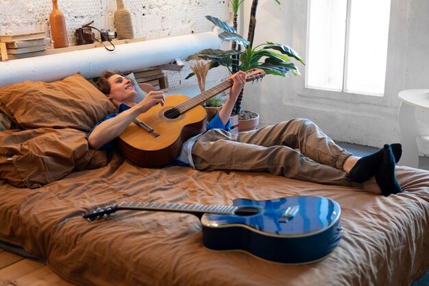 Подросток записывает музыку на гитаре в домашней студии