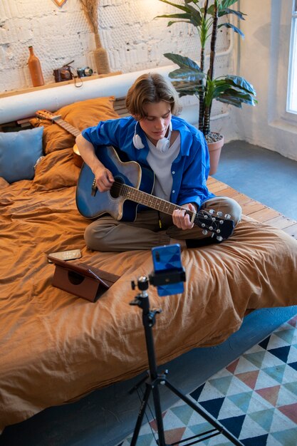 Подросток записывает музыку на гитаре в домашней студии