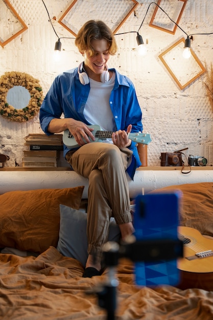 Teenage boy recording music with his guitar at his home studio