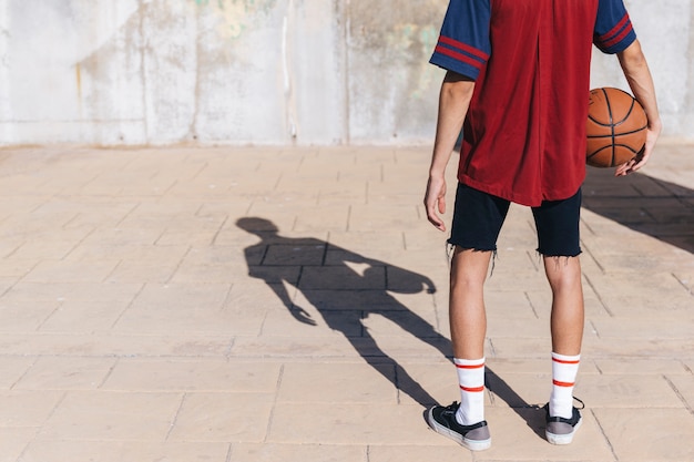 バスケットボール、舗装に立っている十代の少年