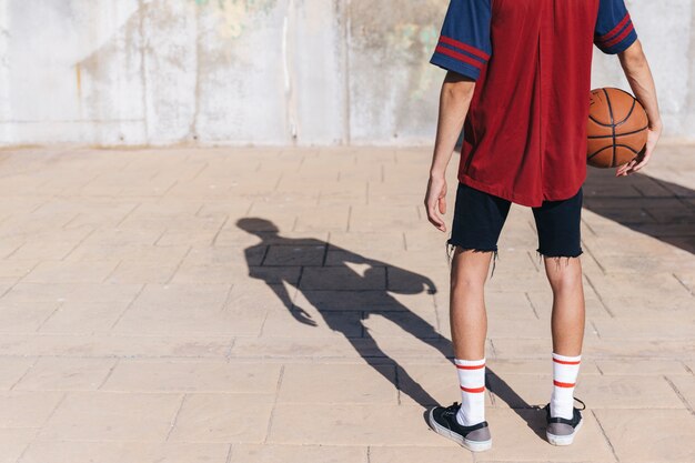 Teenage boy standing on pavement with basketball