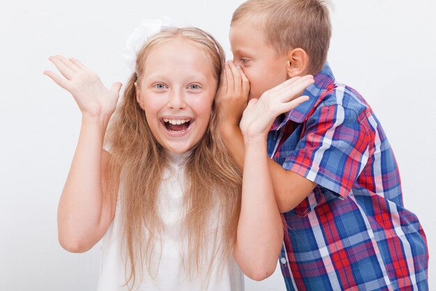 Free photo teenage boy whispering in the ear a secret to teen girl