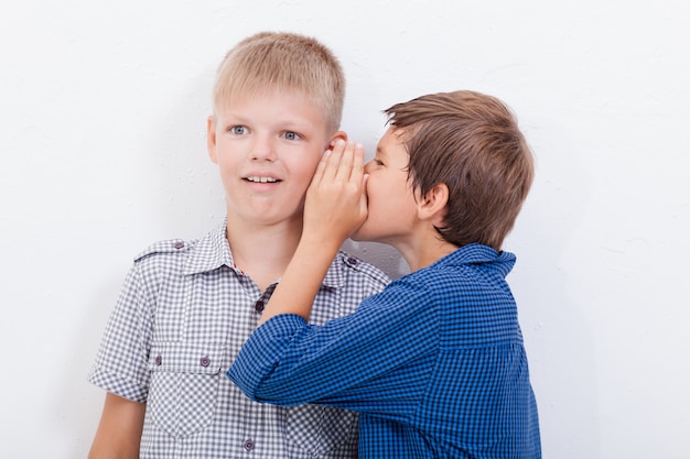 Бесплатное фото Подросток шепчет на ухо секрет friendl на белом фоне