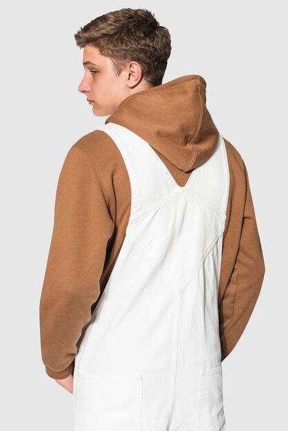 Teenage boy in white dungarees and brown hoodie streetwear photoshoot