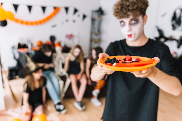 Teenage boy with curly hair and vampire grim giving plate with marmalade