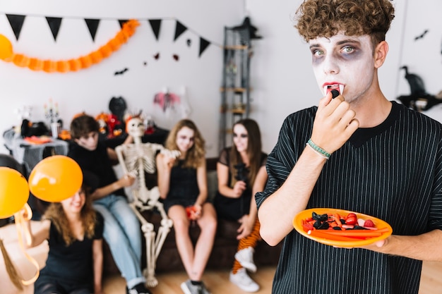 ハロウィーンパーティーでキャンディーを食べる牙を持つ十代の少年