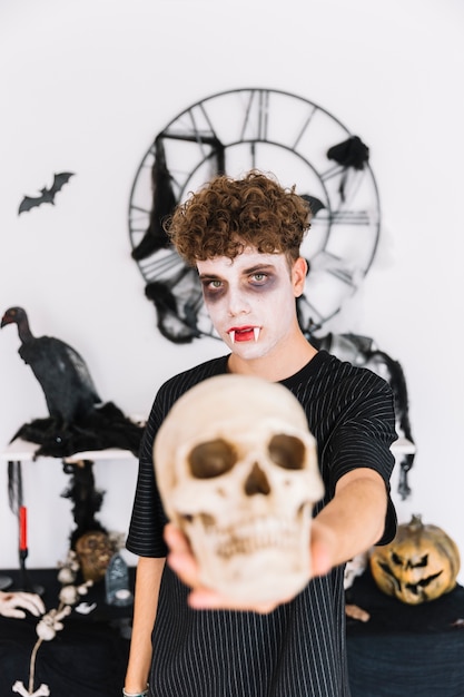 Free photo teenage boy with fangs holding skull