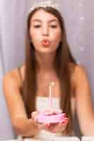 Free photo teenage girl blowing on birthday candle