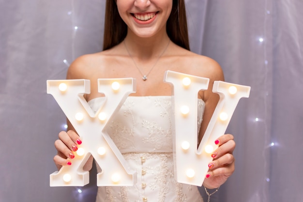 Foto gratuita adolescente che celebra la quinceañera tenendo numeri romani