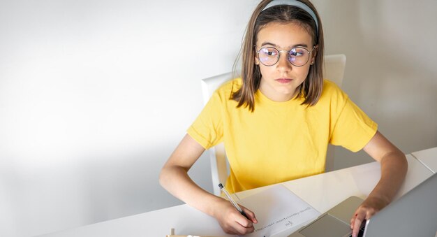 本とラップトップを持って座って宿題をする 10 代の女の子