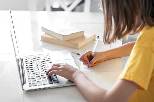 a teenage girl does her homework while sitting with books and a laptop