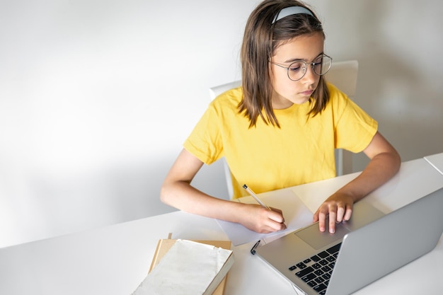 Free photo a teenage girl does her homework while sitting with books and a laptop