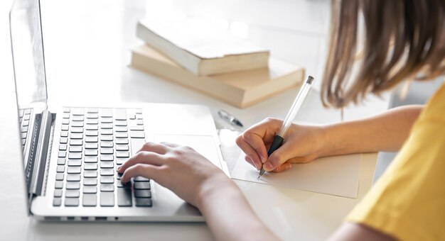 a teenage girl does her homework while sitting with books and a laptop