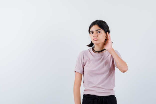 Teenage girl doing a hard of hearing gesture with her right hand on white background