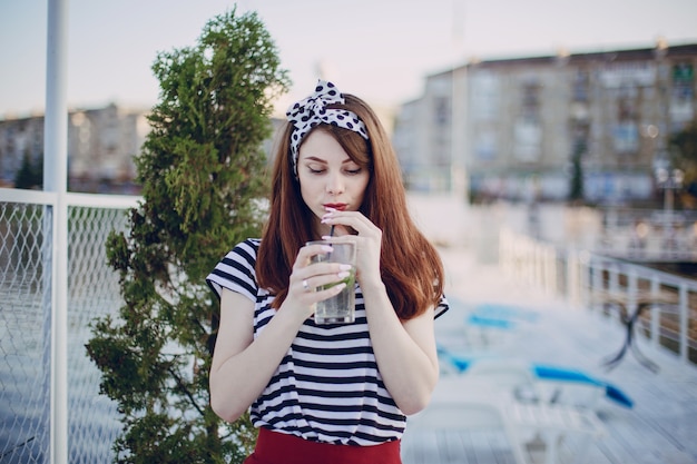 Teenage girl drinking from a glass with a straw