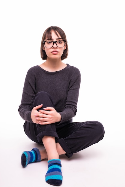 Teenage girl in glasses sitting on the floor isolated