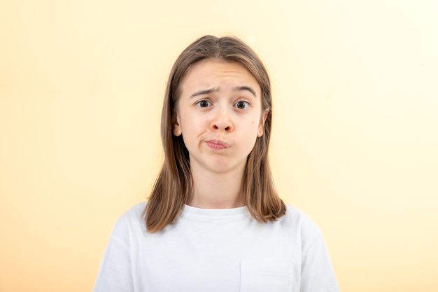 Free photo a teenage girl grimaces with displeasure on a white background isolated