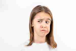 Free photo a teenage girl grimaces with displeasure on a white background isolated