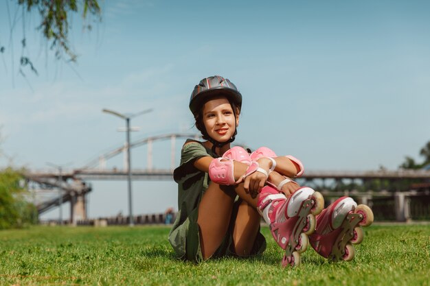 Teenage girl in a helmet learns to ride on roller skates outdoors